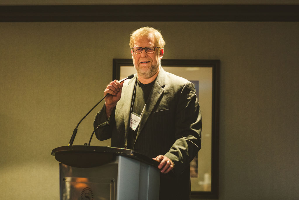 A photo of Jonathan Bengtson delivering a speech during the Ron MacDonald Award Ceremony.